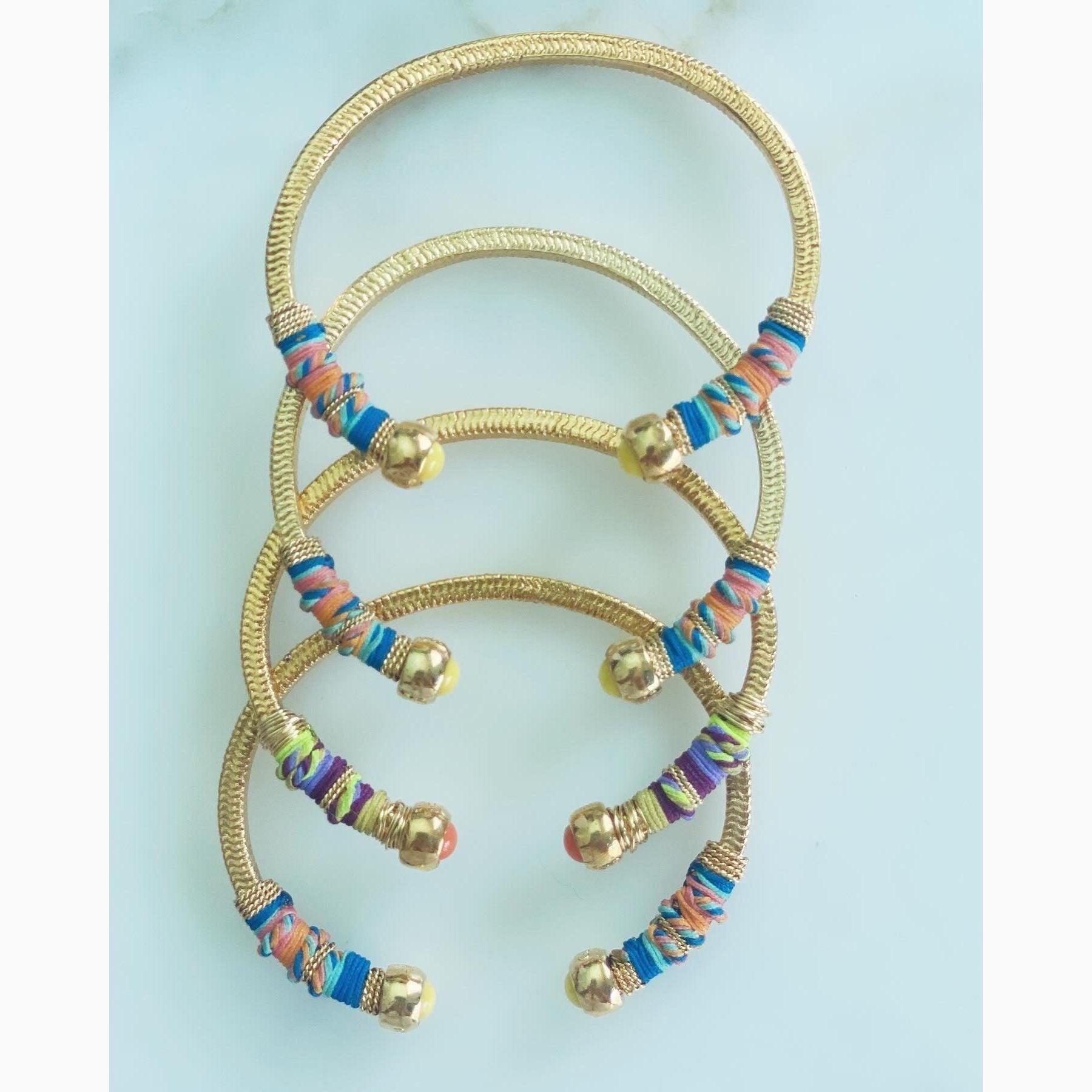 Gold plated bracelet embellished with tinted threads and gold plated chains.  The bracelet is adorned with glass beads at ends. Adjustable size.  Product Details  Yellow Gold Plated Cotton Rope or all metal Width: 0,6 cm; Circumference: 14,5 cm