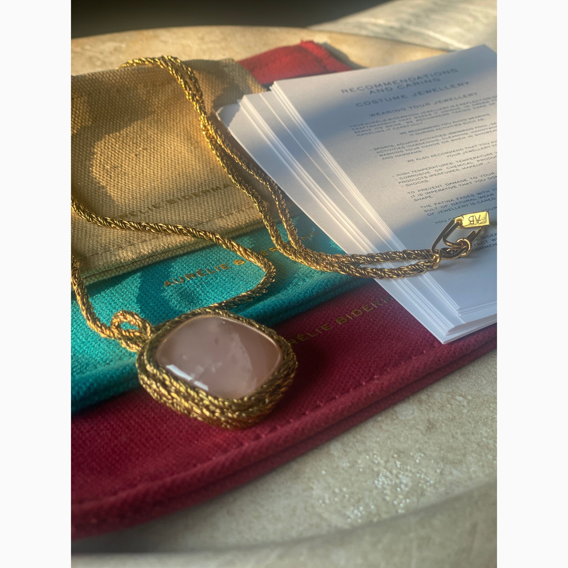 Aurelie Bidermann Miki necklace against beautiful packaging and caring guides