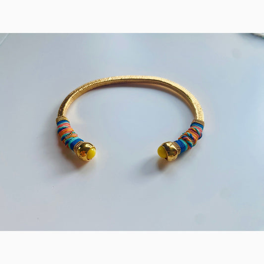 Gold plated bracelet embellished with tinted threads and gold plated chains. The bracelet is adorned with glass beads at ends. Adjustable size. Product Details Yellow Gold Plated Cotton Rope or all metal Width: 0,6 cm; Circumference: 14,5 cm