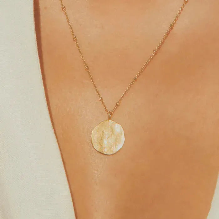 Minimalist and delicate, this necklace feels like a precious ancient vestige. Its hammered full moon design will protect you day and night.